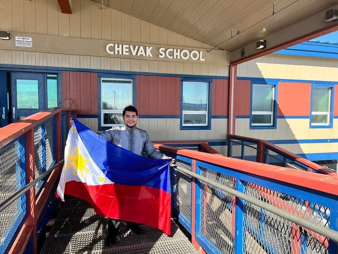 Cesar holds the Philippine flag outside Chevak School in rural Alaska, during his own exchange placement.