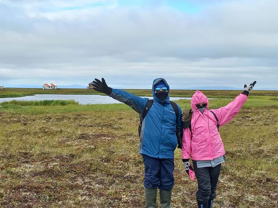 Cesar and another J-1 teacher, arms raised, at the old village site of Chevak, Alaska, during a staff in-service.